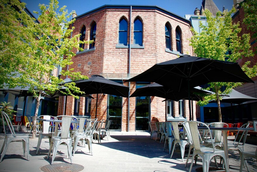 Exterior of Pearson and Murphy's Cafe with silver chairs and large black umbrellas.