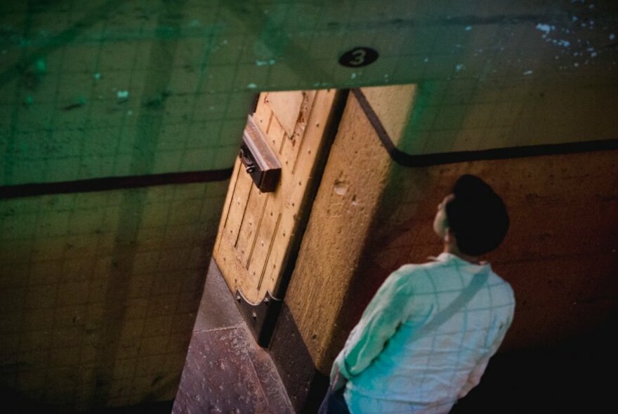 A visitor to the jail looking in through the door of a cell.