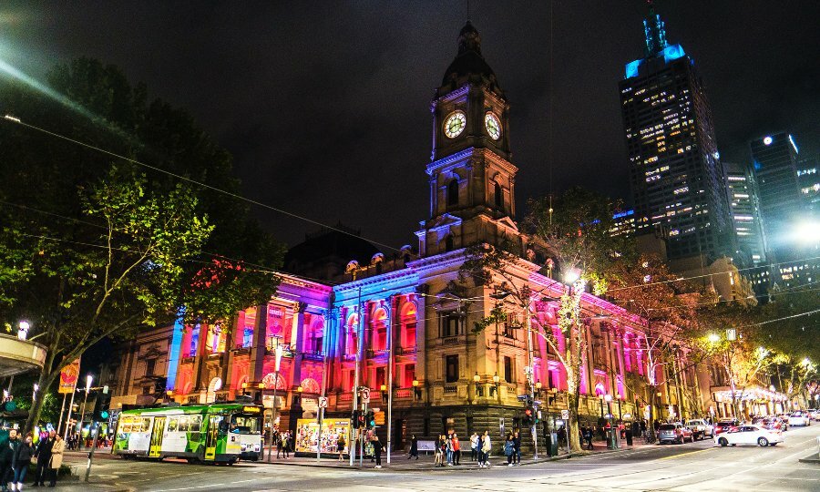 Melbourne Town Hall at night lit up with colourful lights for the Comedy Festival.
