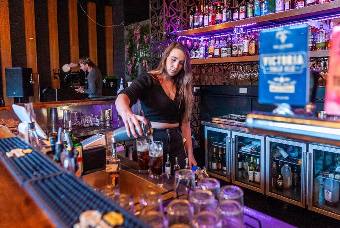Woman behind the bar pouring cocktails.