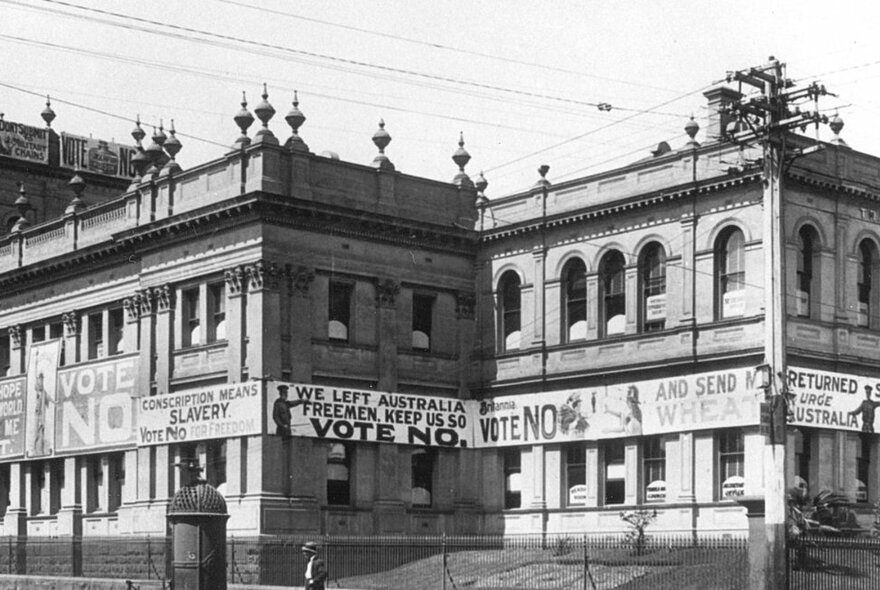 An old black and white image of the Victorian Trades Hall building with protest banners around it. 