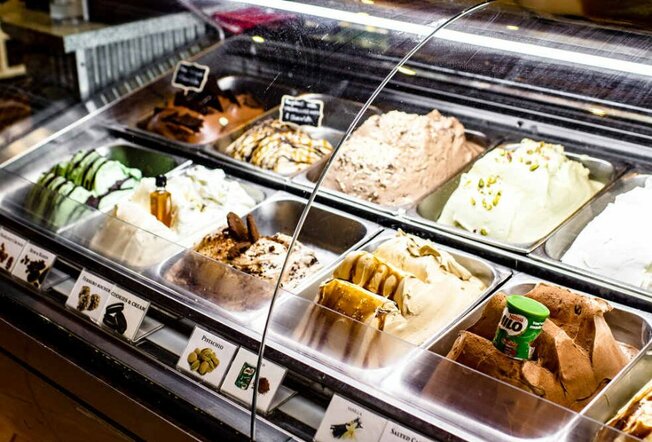 Tubs of ice-cream behind a plastic shield at a gelateria
