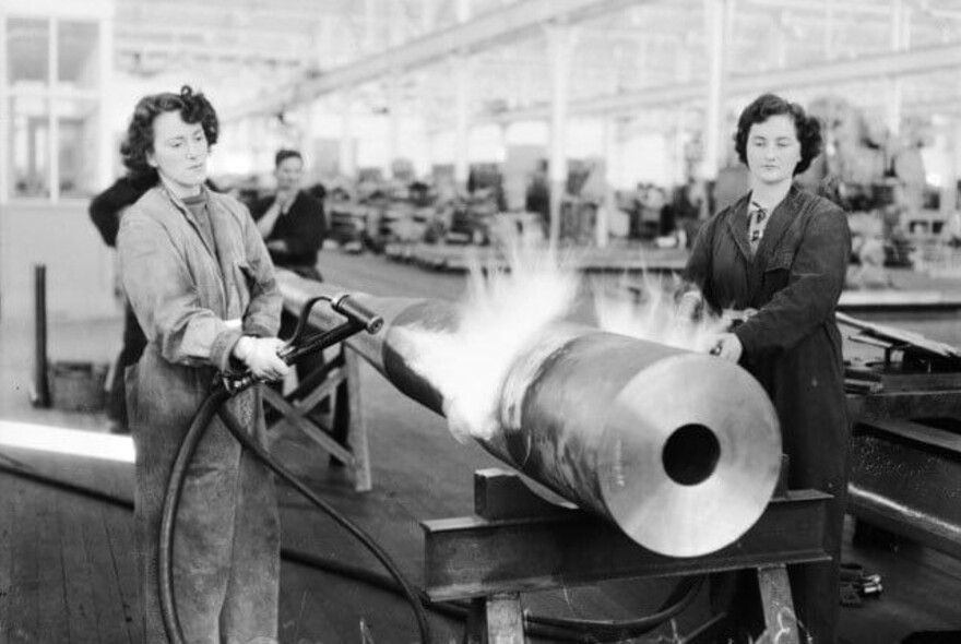 Historic photo of two women working with heavy machinery.