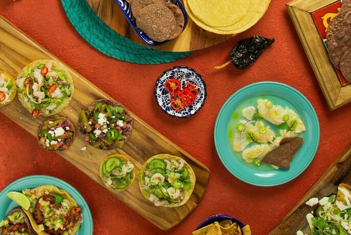Table with various plates of Mexican food, viewed from above.