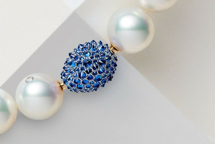 Close up of pearl bracelet with one bright blue jewelled link.