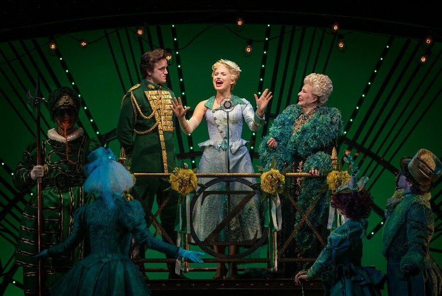 A scene from WICKED the Musical, with members of the cast on stage in green costumes.