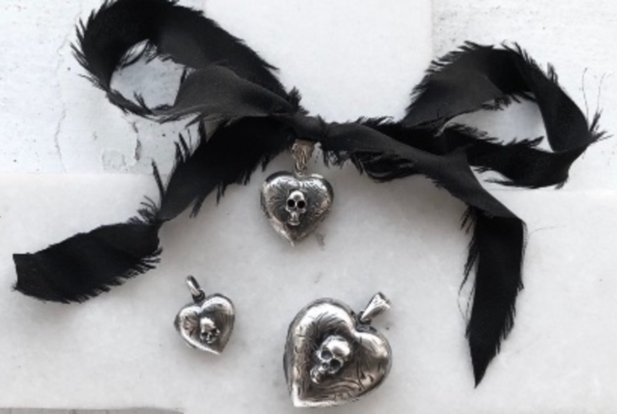 Gothic-style jewellery pieces featuring skulls in hearts and a black fringed bow.
