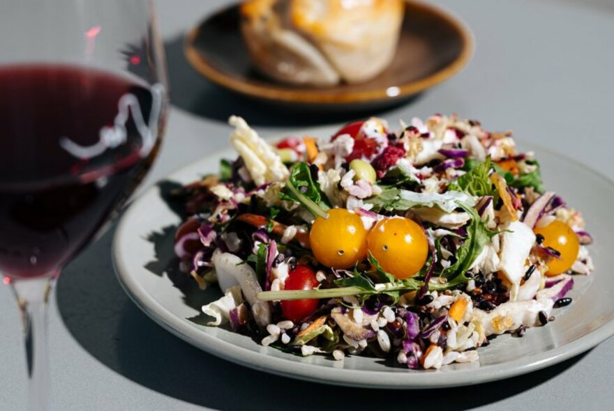 A colourful salad with a a glass of red wine. 