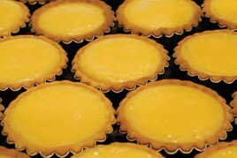 Close-up of round lemon tarts with pleated edges.