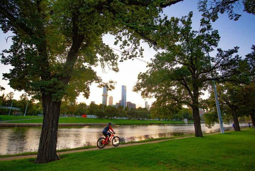 A man on a bike riding past the river.