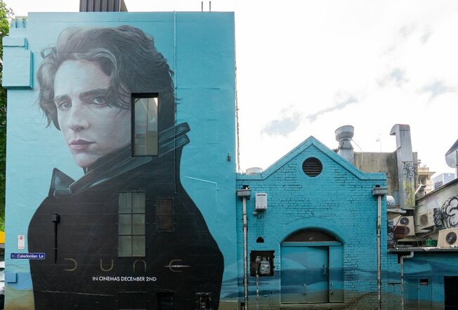 Image of Timothee Chalamet as his role as Paul Atreides in Dune. Mural has a turquoise background.