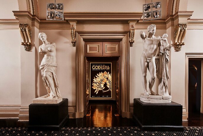 Two classical statutes on display against a wall. 