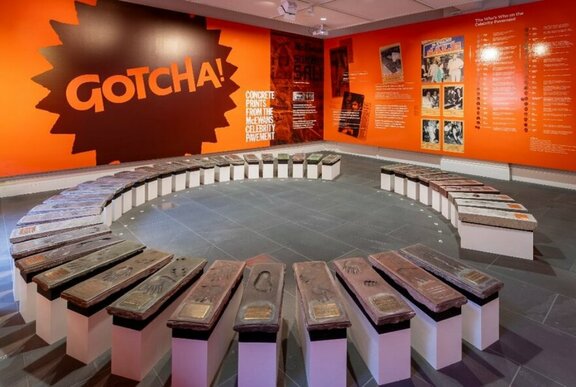 Exhibition room with orange walls and circular display of hand casts.