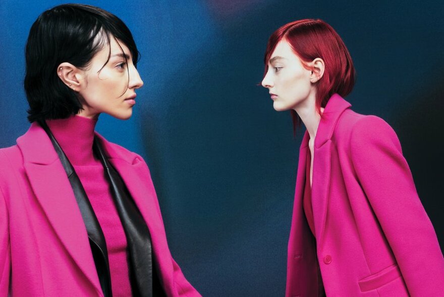 Two woman in bright pink coats facing off.