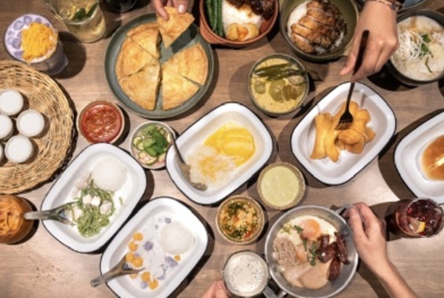 Overhead view of many dishes on a table, with hands using spoons.