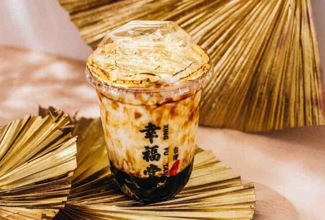 A container of bubble tea with gold leaf on top