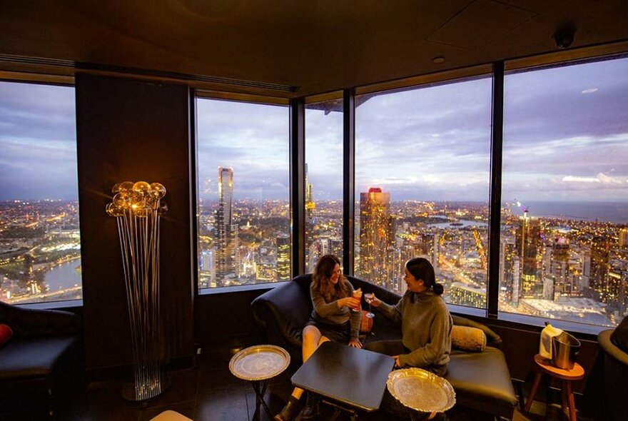 Two people enjoying drinks at a sophisticated cocktail bar on the 55th floor.