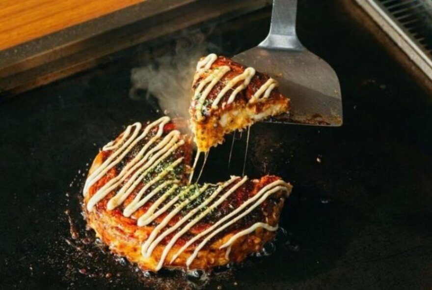 Okonomiyaki savoury Japanese pancake on a hot grill.