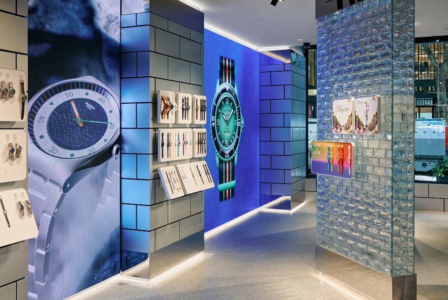 Store interior with shimmering brick columns, large images of watches and display shelves.
