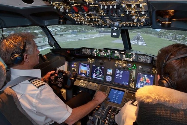 Two people sitting in the cockpit of a Boeing 737 jet airliner for a simulated flight experience. 