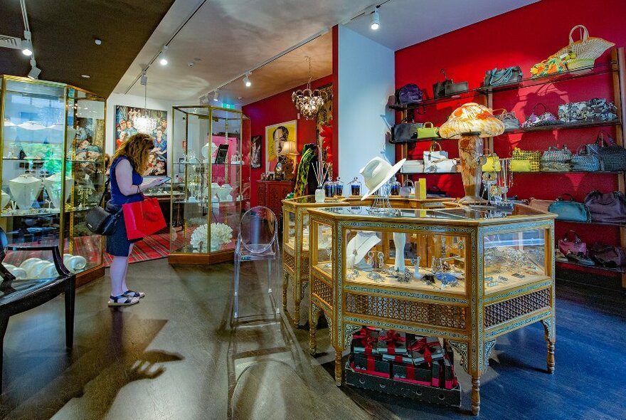 A woman browsing in a boutique filled with hats, bags and jewellery cabinets.