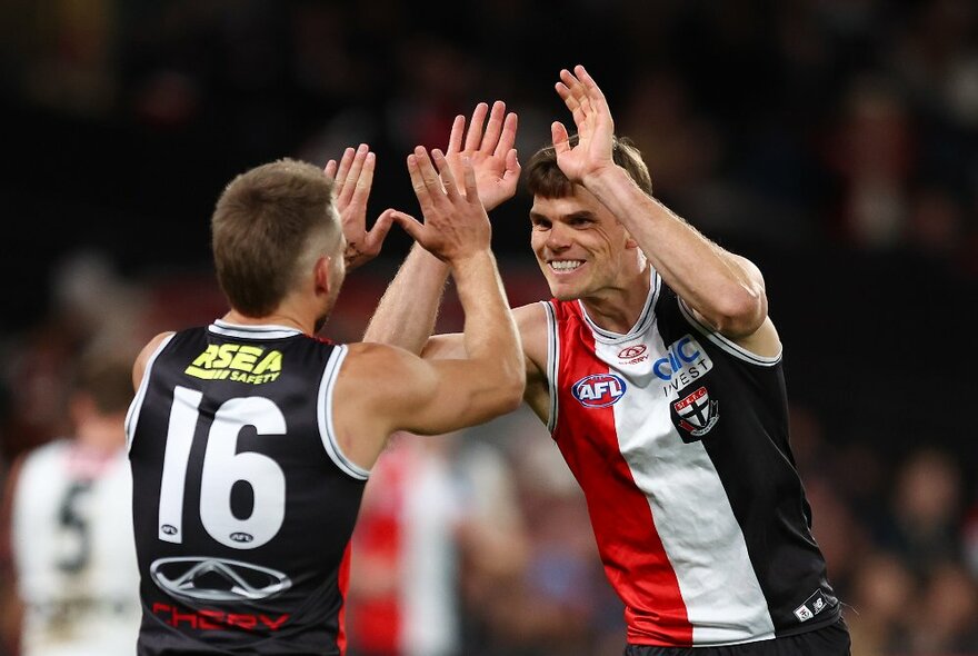 Two St Kilda AFL football players high-fiving during a match.