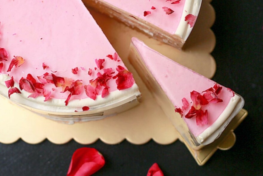 Pink cream cake with a slice cut out. 