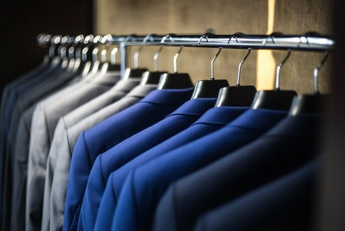 Men's suits hanging on clothing rack.