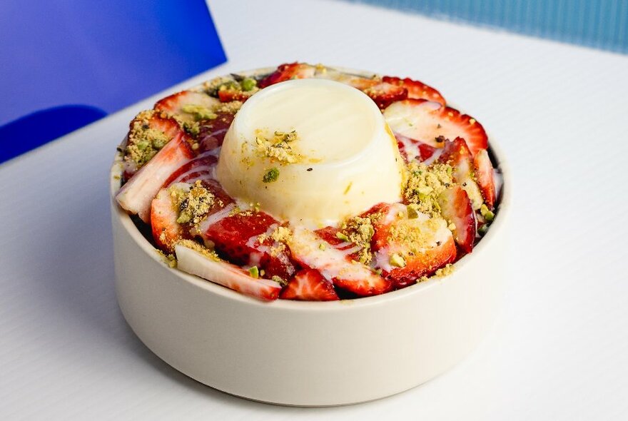 A bowl of cut strawberries with a white panna cotta in the middle.