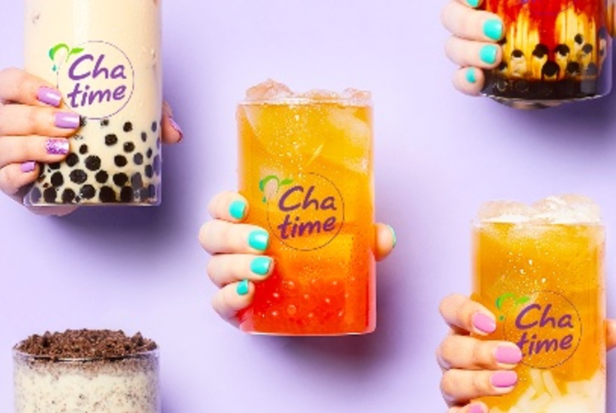 Hands holding different glasses of bubble tea.