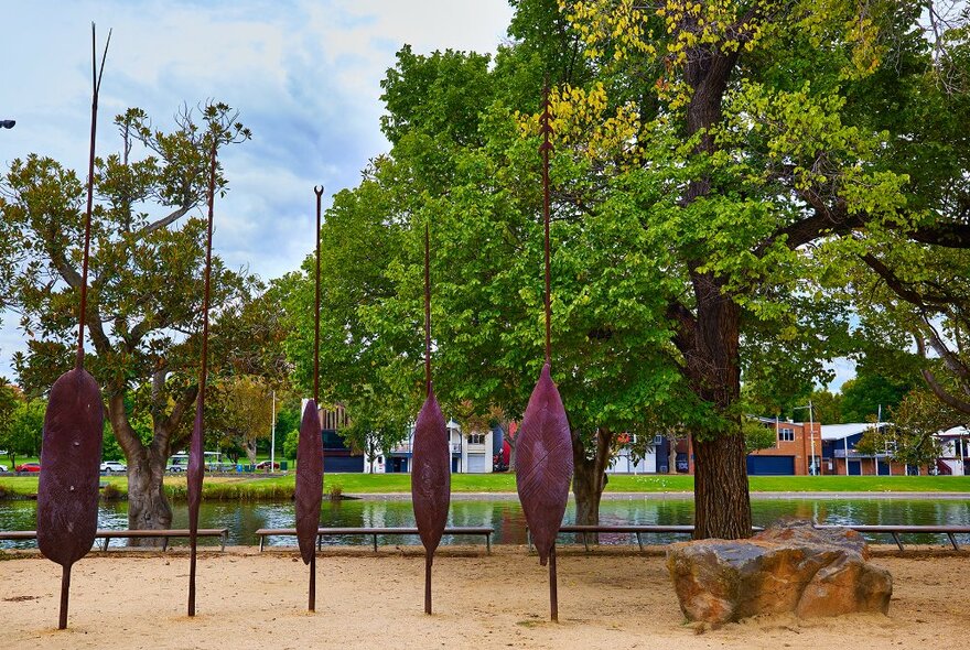 An art installation featuring 5 large metal shields next to the river.