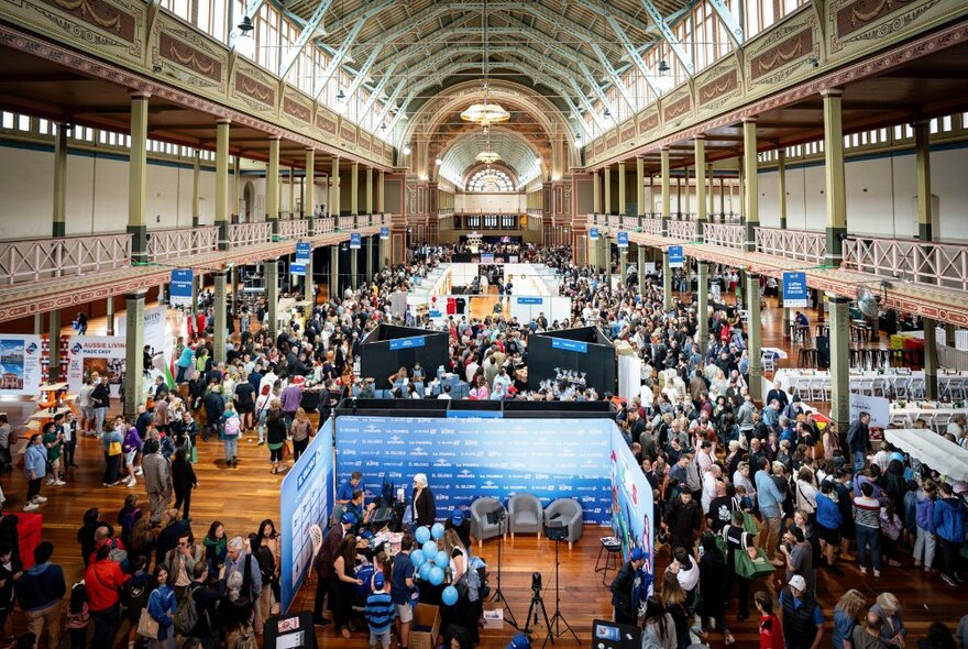 Royal Exhibition Building interior with crowds of marketgoers perusing stalls and milling through the large venue.