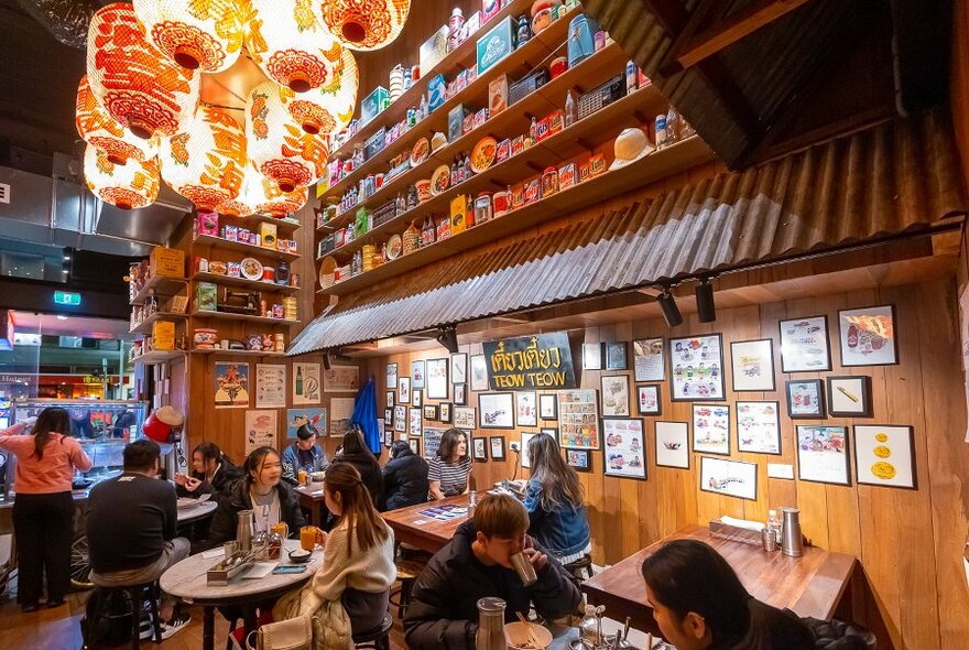 A Thai restaurant with red lanterns hanging from the ceiling and pictures on the wall.