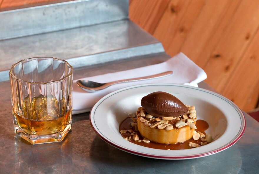 Dessert with chocolate mouse and peanuts with a tumbler of whisky.