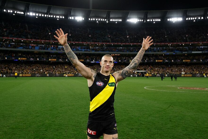 Richmond player Dustin Martin holds up his hands in the air in the middle of the MCG. 