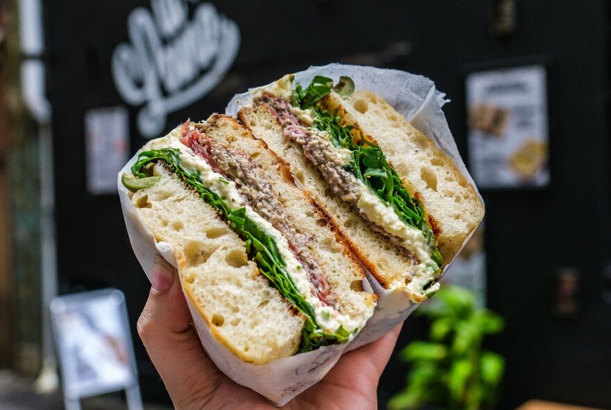 A focaccia sandwich with meat and salad in it.