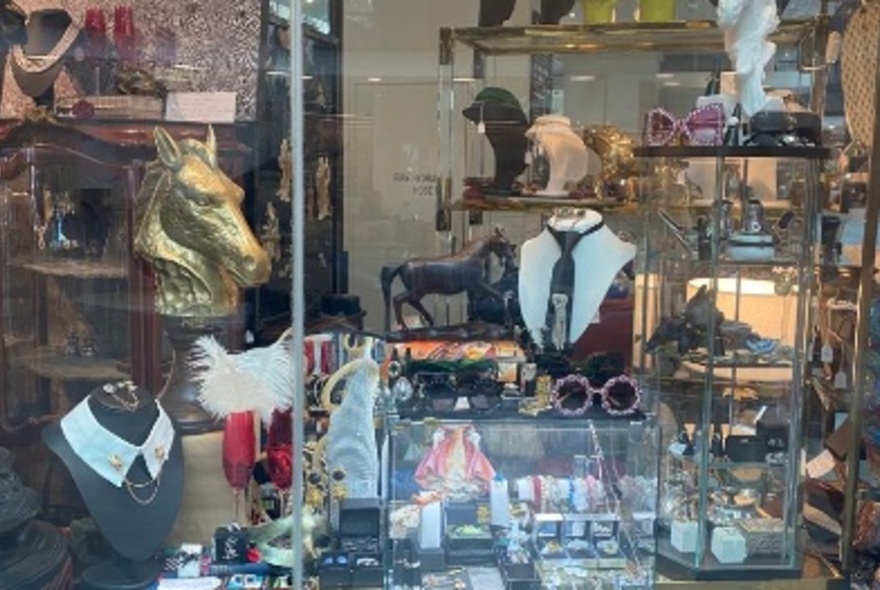 A shop window with many items on display in glass cabinets, mostly trinkets and small items of jewellery.