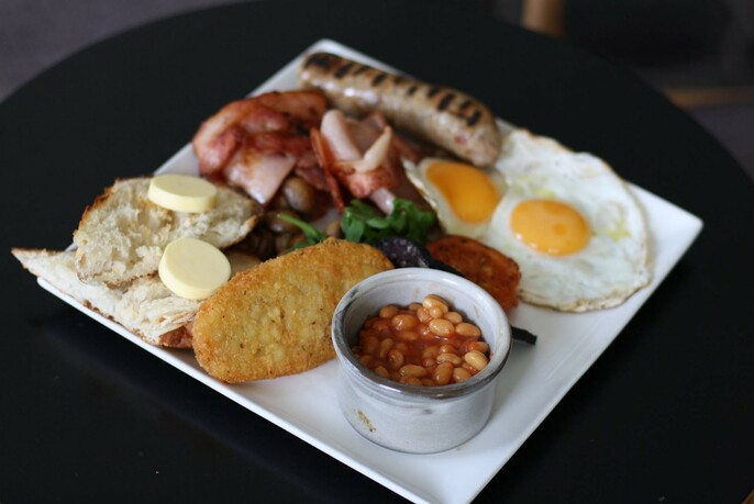 Traditional English fried breakfast of bacon and eggs, beans and sausage, plus a hash brown.
