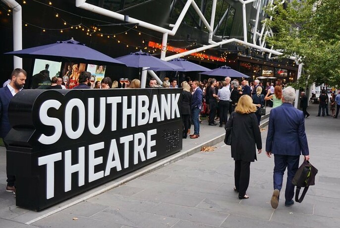 People walking past a large Southbank Theatre sign on Southbank Boulevard.