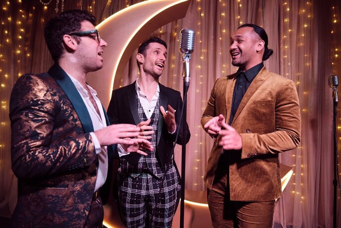 Three men singing around an old-fashioned microphone. 