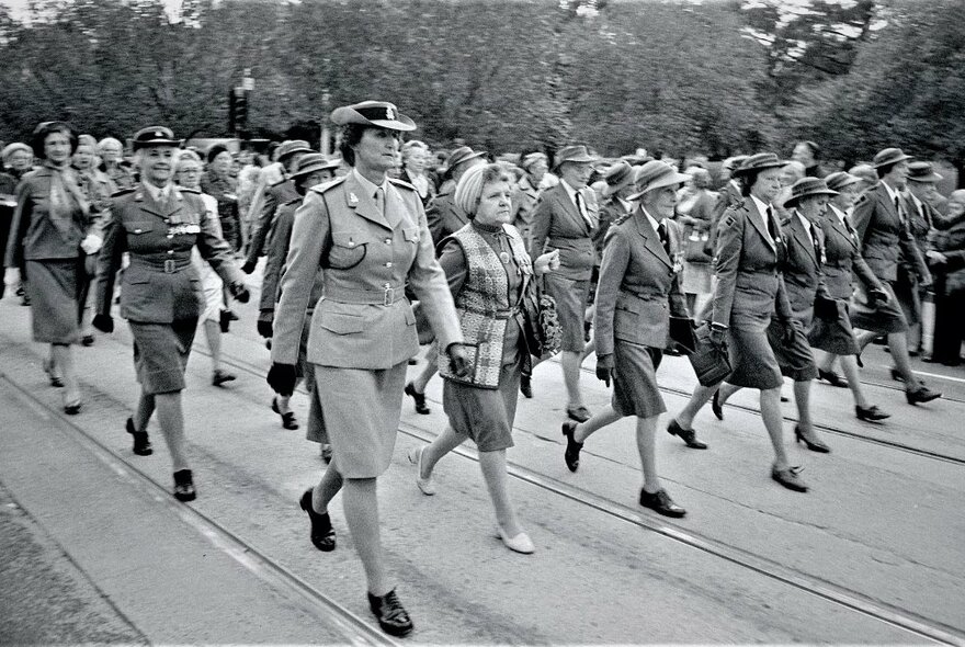 A street parade of women in defence force uniforms; black and white image dating from the mid-1970s.
