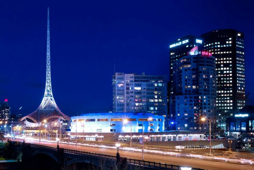 Princes Bridge and iconic spire of the Arts Centre Melbourne illuminated at night.