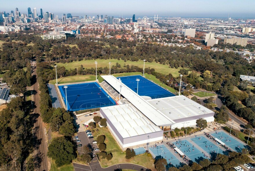 Aerial view of the outside courts of the State Netball and Hockey Centre and surrounding parkland.