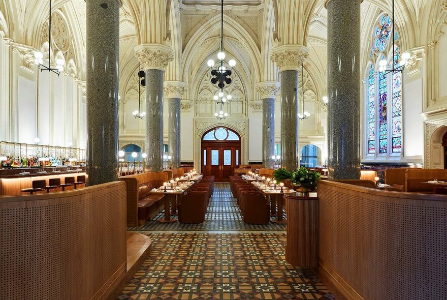 A restaurant in an historic building with arches, tiled floors and stained glass windows.