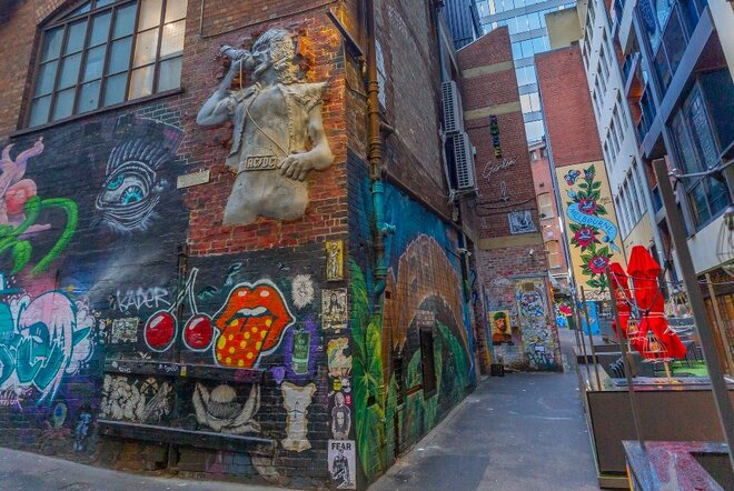 A sculpture of a singer on a brick wall surrounded by street art.