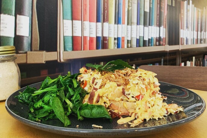 A row of books above a plate of rice with vegetables.