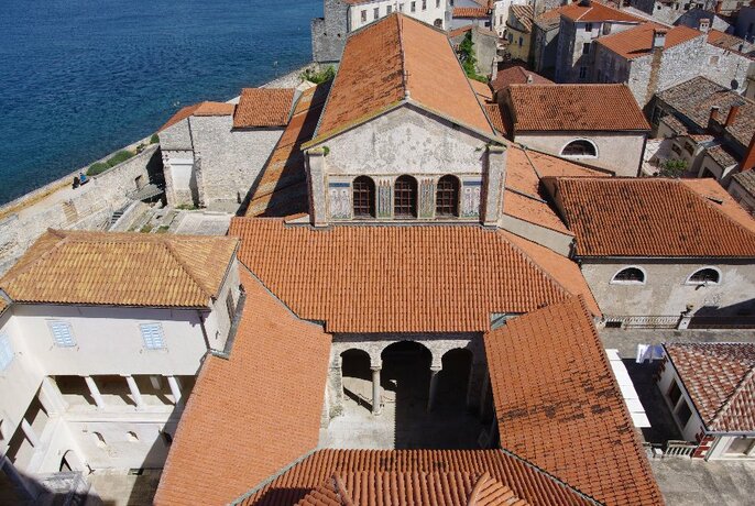 Terracotta rooftops of church and cloisters by the sea.