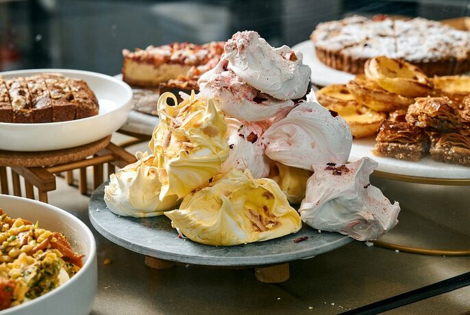 Meringues take the centre of a table surrounded by sweet bakery treats.