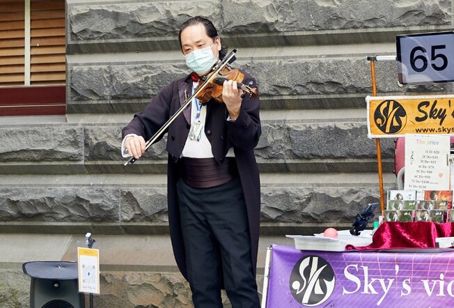 A violinist busker wearing a tuxedo.