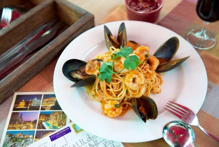 Postcards next to a bowl of seafood marinara with mussel shells.